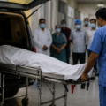Hospital staff respectfully transferring a deceased person while family members and medical personnel observe in a healthcare facility.
