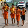 Four siblings walk on the Kanwar Yatra in orange attire while praying for help with their school fees
