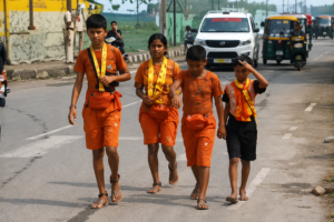Four siblings walk on the Kanwar Yatra in orange attire while praying for help with their school fees